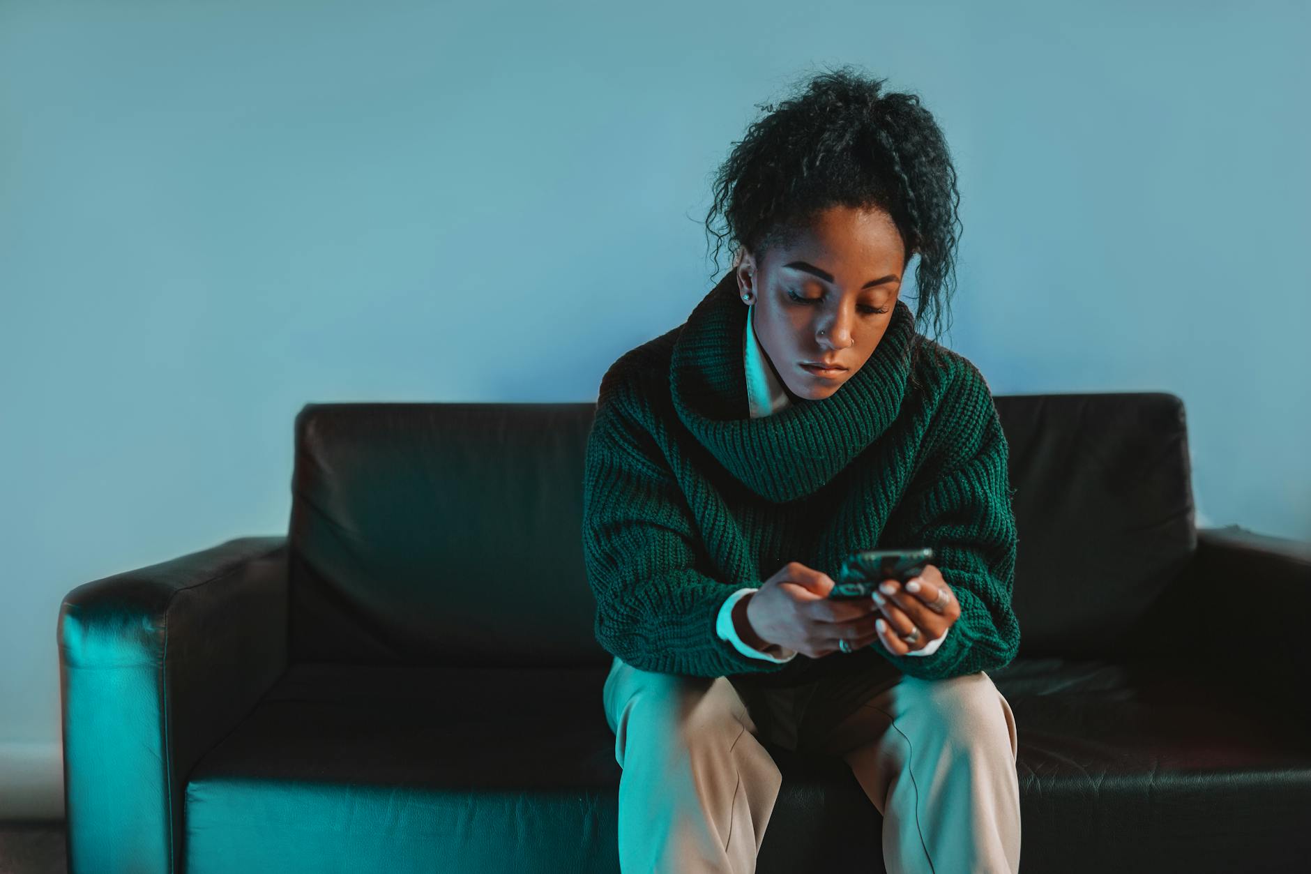 a woman in green sweater sitting on black couch